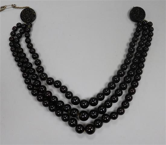 A triple strand simulated dark amber graduated bead choker necklace with carved disc terminals.